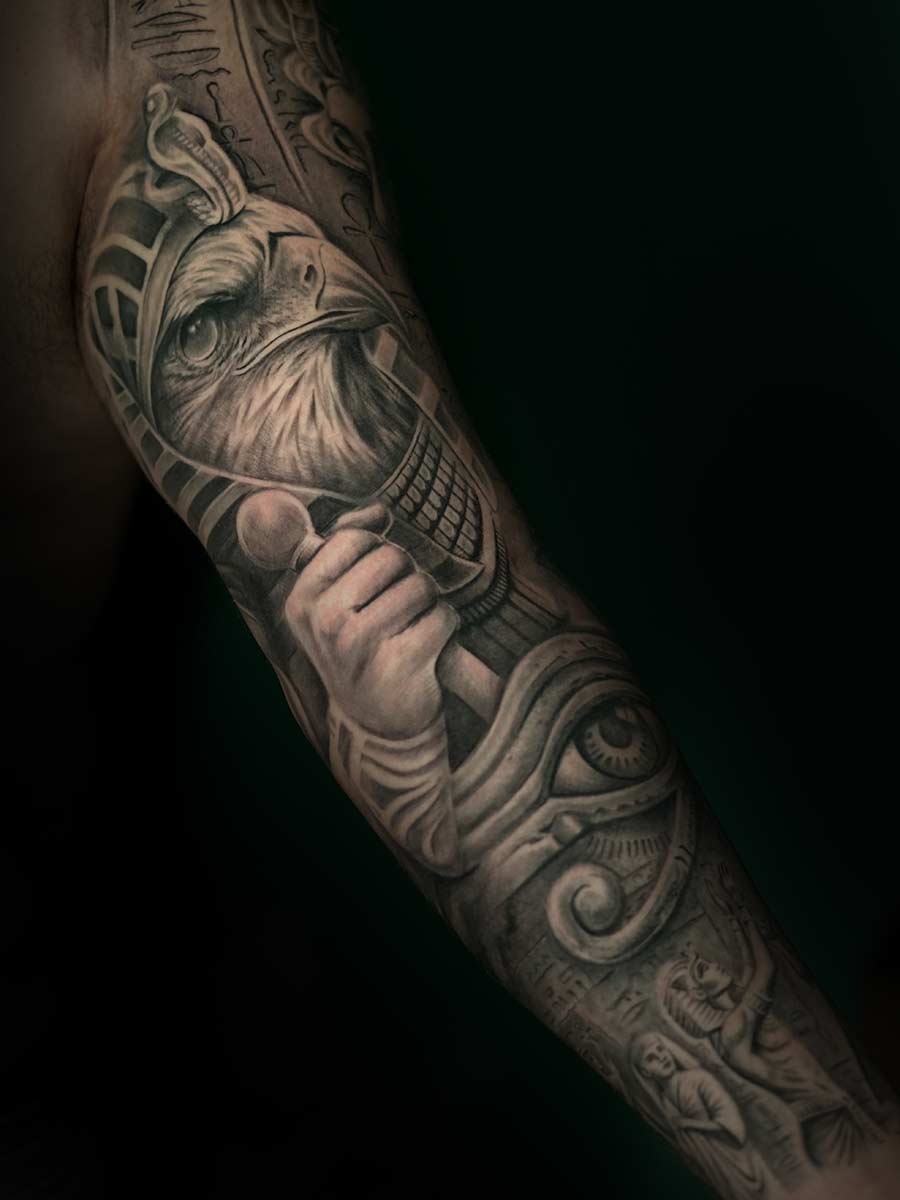 Black-and-grey inner sleeve tattoo with Horus and hieroglyphs